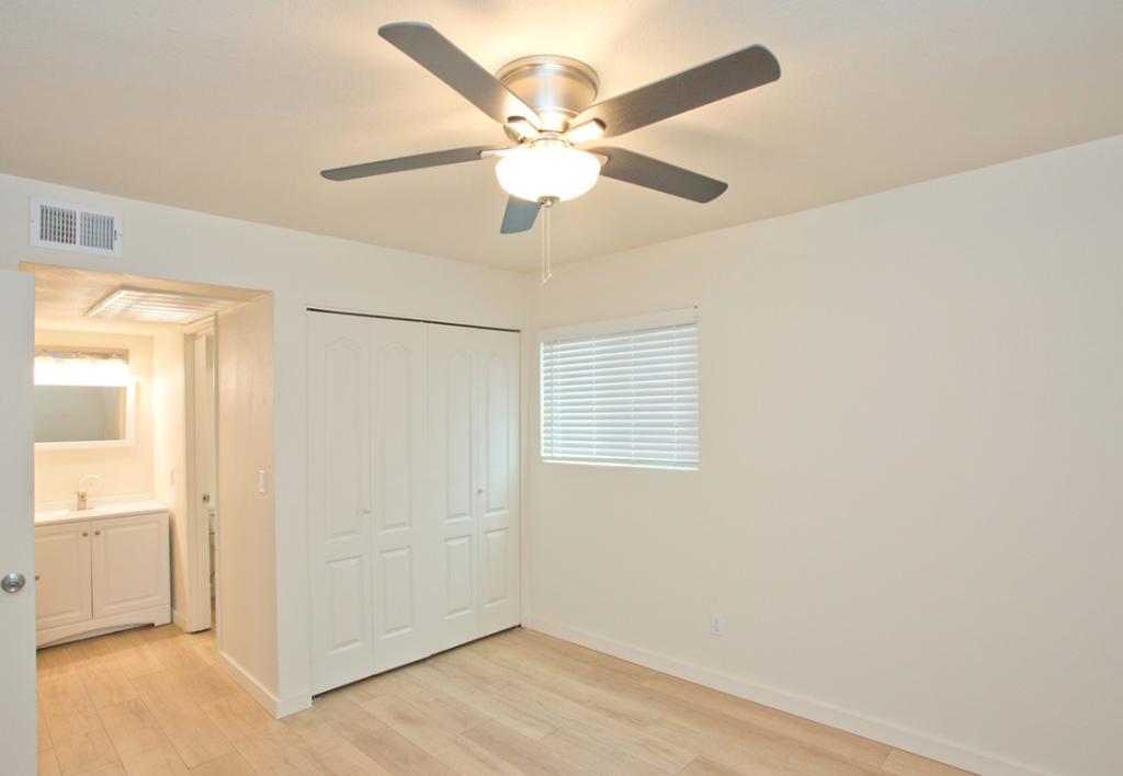 a living room with a ceiling fan and a door to a bathroom