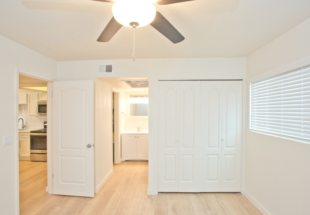 a living room with a ceiling fan and a door to a kitchen