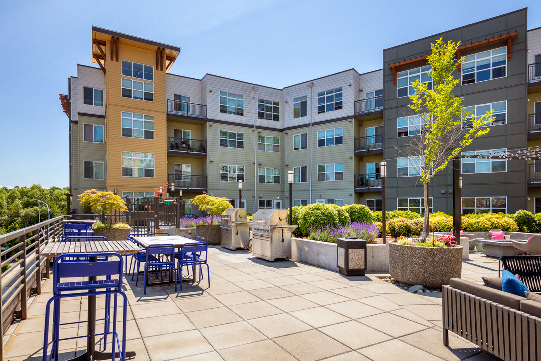 a patio with tables and chairs in front of an apartment building