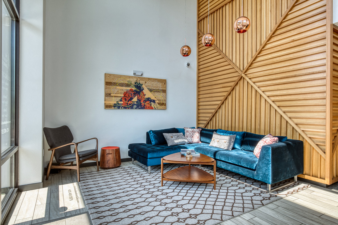a living room with blue couches and a wooden wall