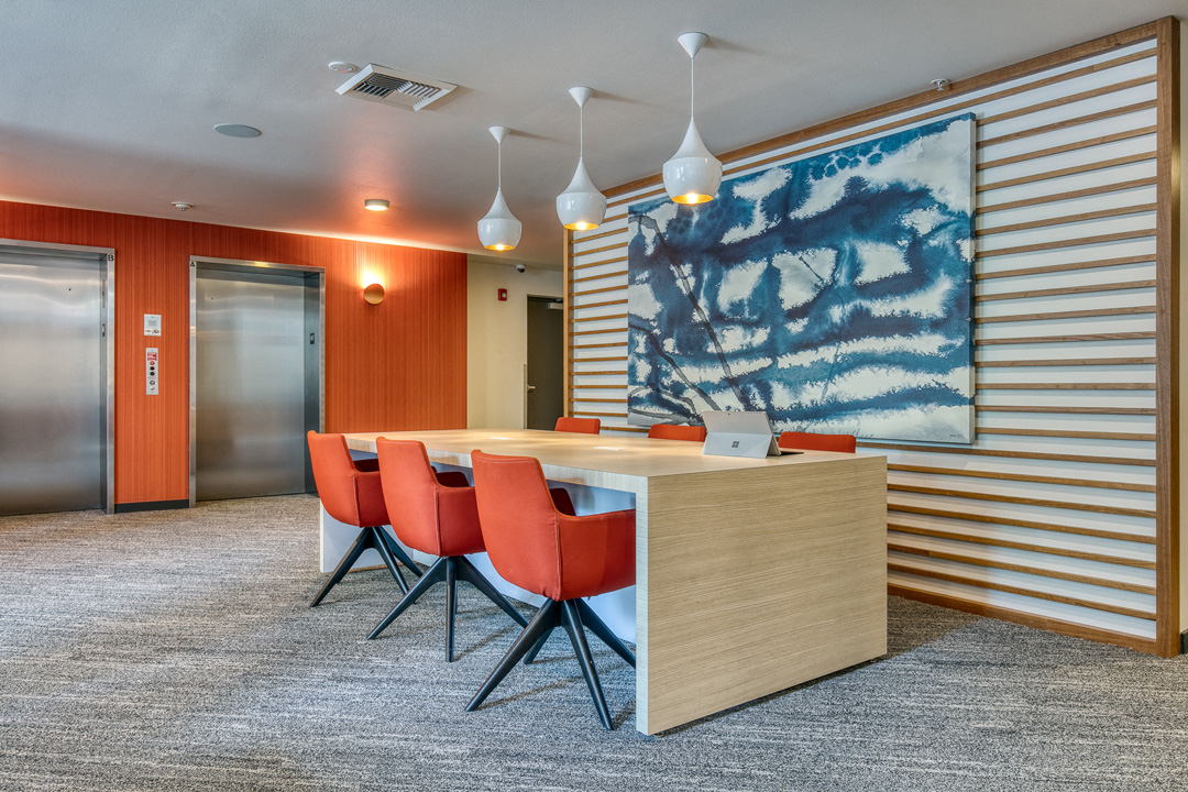 a conference room with orange chairs and a table and a large artwork