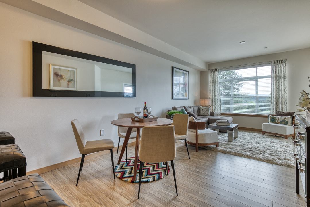 the living room of an apartment with a dining table and chairs