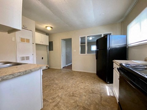 A kitchen with a black fridge and white cabinets.