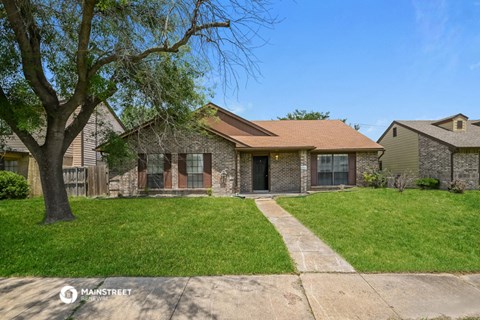 a small brick house with a yard and a tree