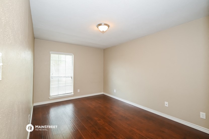 the spacious living room with hardwood flooring and a window