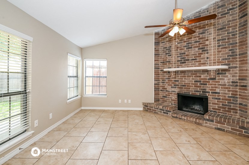 a living room with a brick fireplace and a ceiling fan