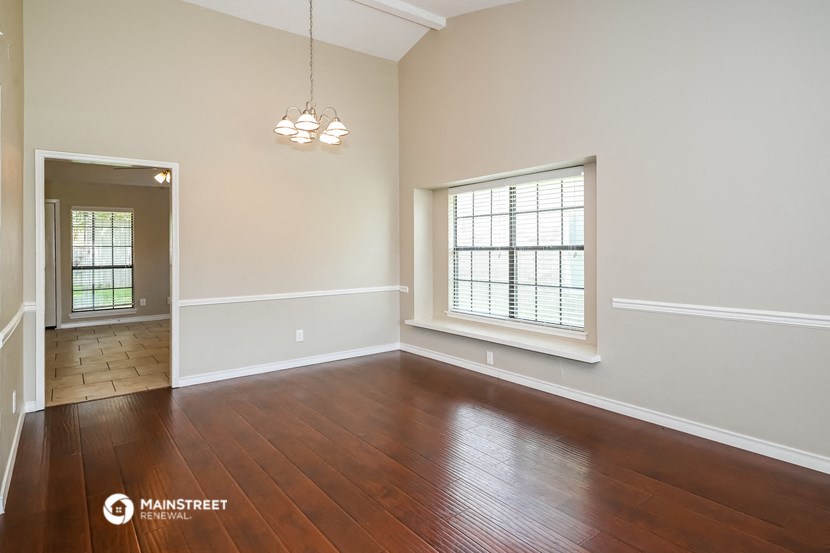 an empty living room with wood floors and a window
