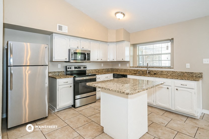 a kitchen with white cabinets and granite counter tops and stainless steel appliances
