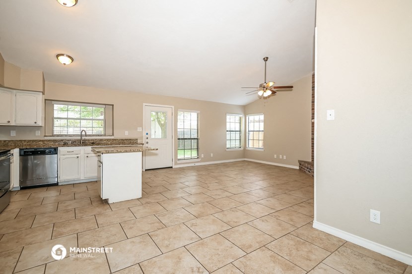 the kitchen and living room are spacious with tile flooring and a ceiling fan