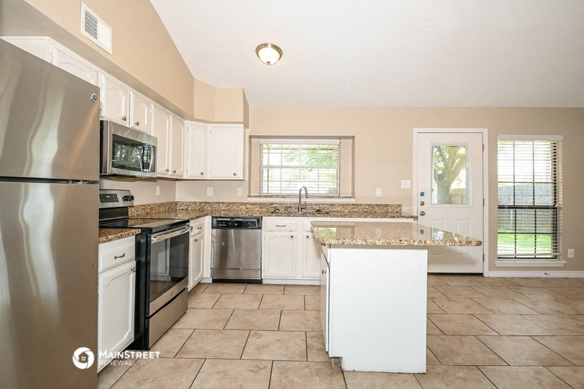 the kitchen has a large island and stainless steel appliances
