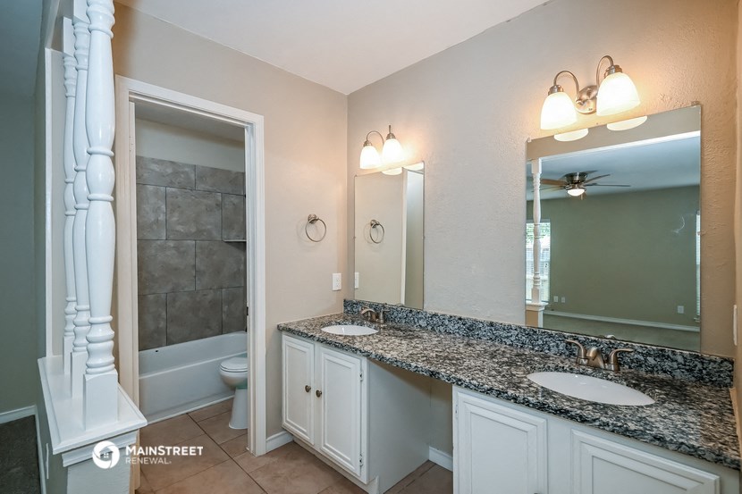 the master bathroom has dual sinks and a large mirror