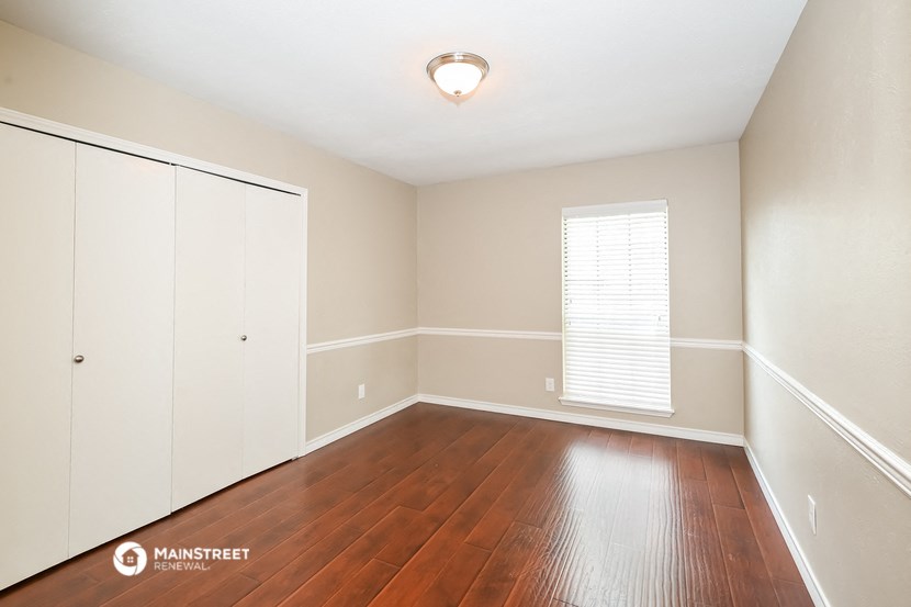 the spacious living room with hardwood flooring and white walls