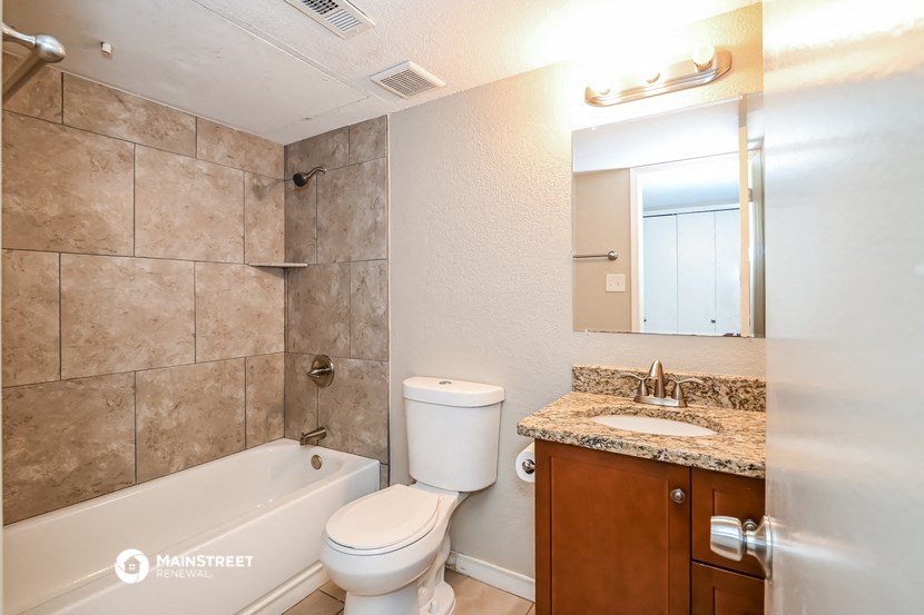 a bathroom with a toilet sink and tub and a mirror