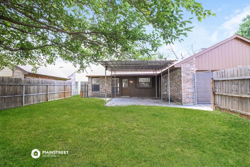 a backyard with a garage and a grass yard and a fence