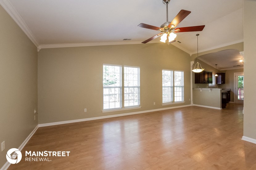 an empty living room with a ceiling fan and windows