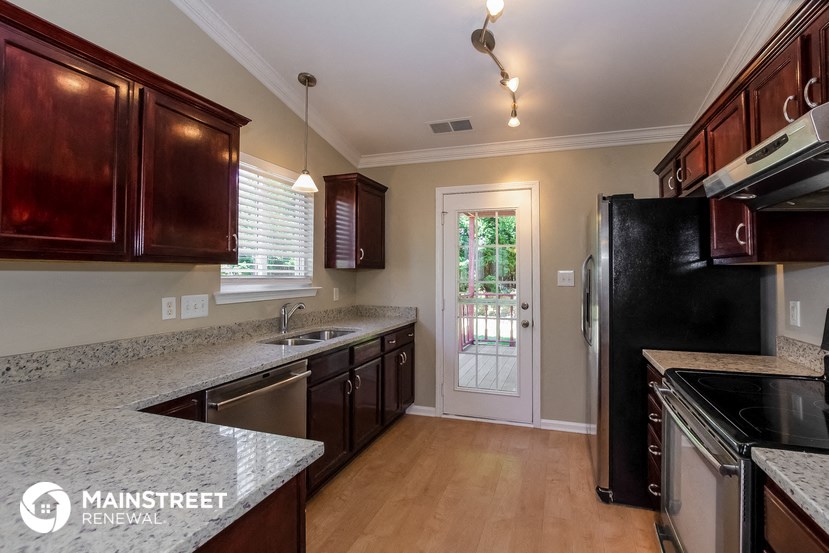 a kitchen with wood cabinets and granite counter tops and a black refrigerator