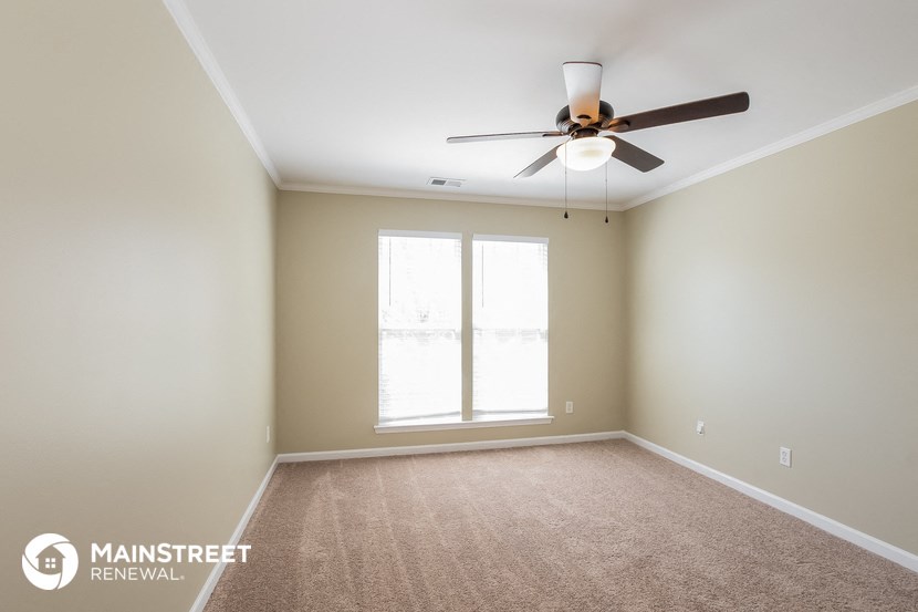 an empty room with a ceiling fan and a window