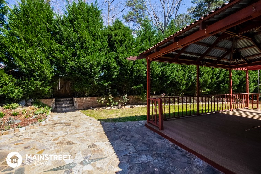 a patio with a gazebo and trees in the background