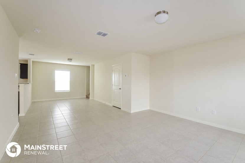 an empty living room with tile floor and white walls