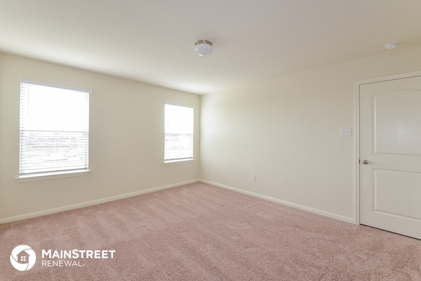 an empty room with a door and two windows