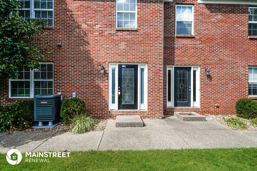 a brick building with a black door and a sidewalk in front of it