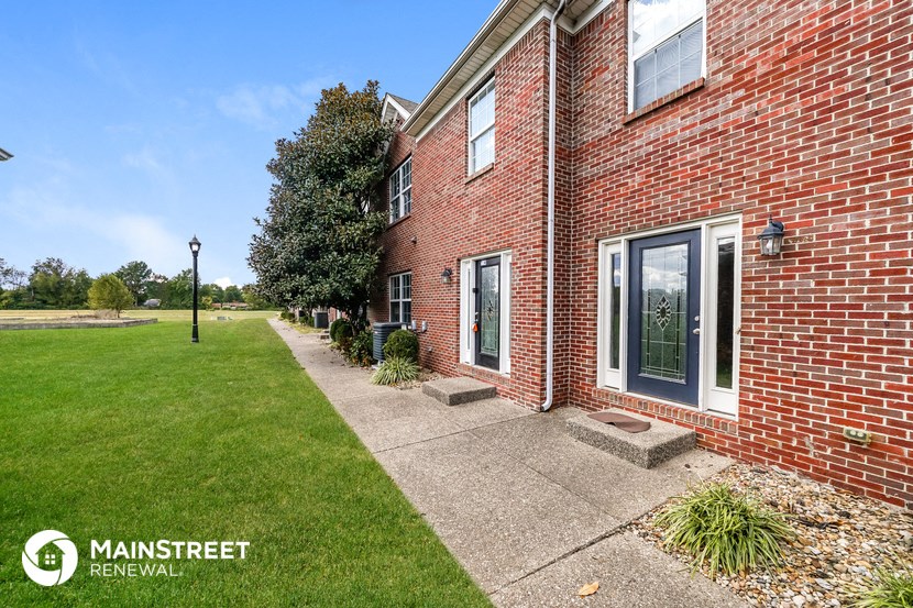 a side view of a brick house with a lawn and a sidewalk