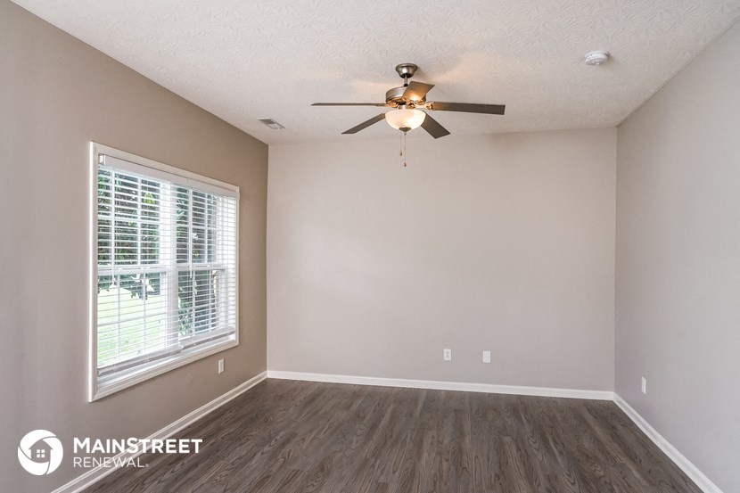 the spacious living room with ceiling fan and window