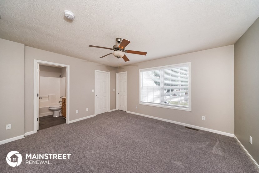 the living room is spacious and has a ceiling fan