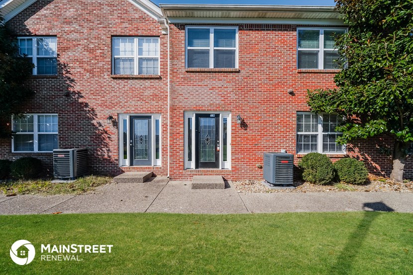 a side view of a brick house with a sidewalk and grass
