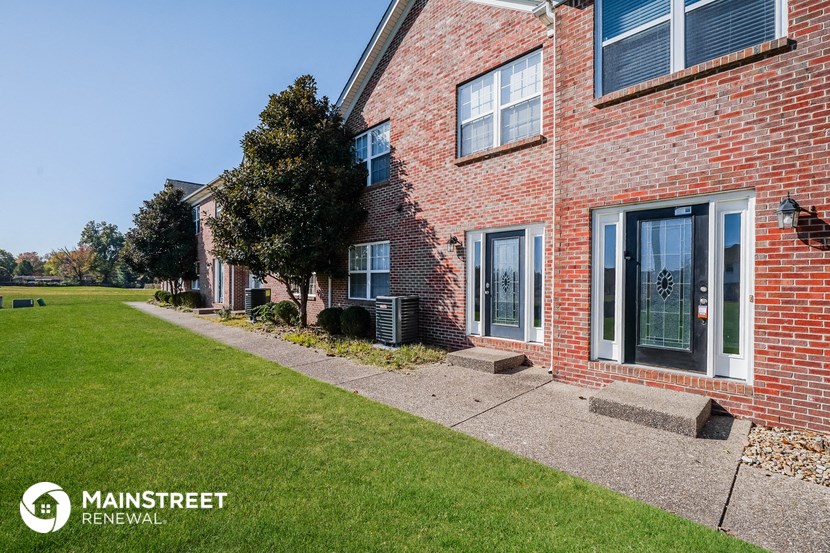 a side view of a brick house with a lawn and a sidewalk