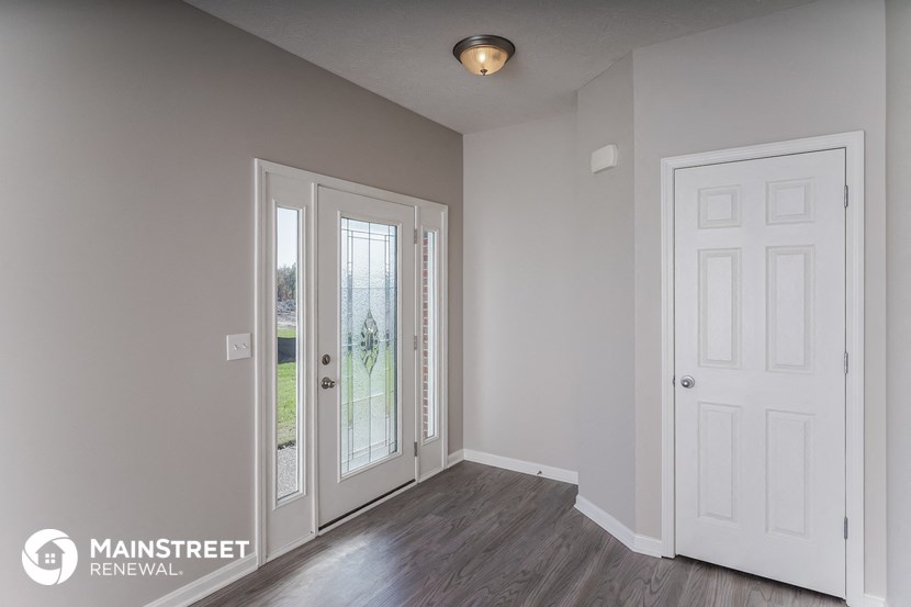 the living room of a house with a white door and a window