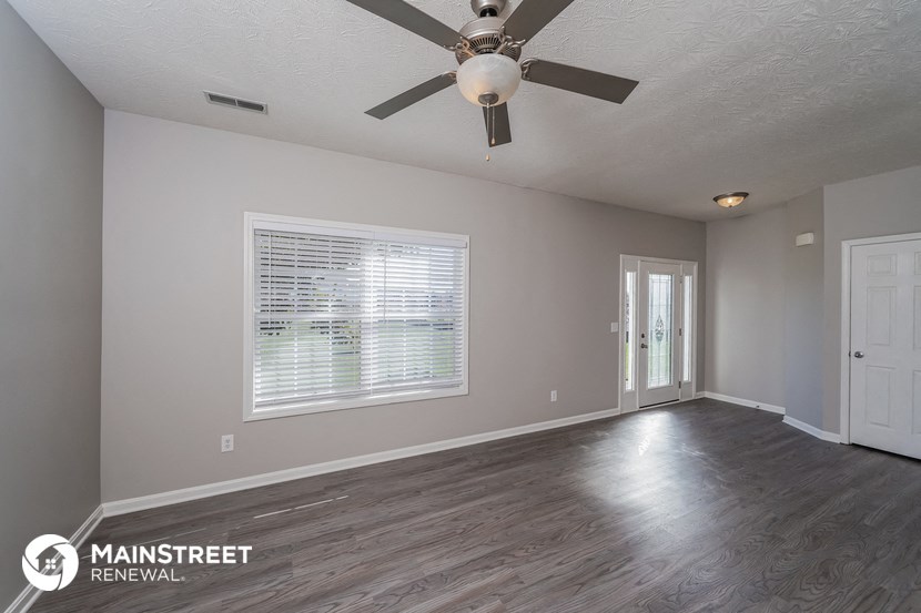 the living room of an empty house with a ceiling fan
