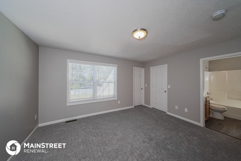 the spacious living room of this manufactured home has carpeted floors and a large window