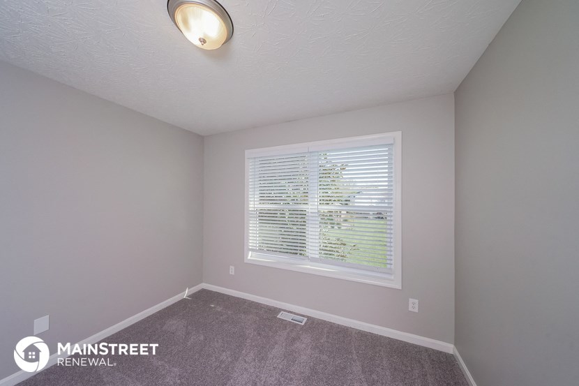 the upstairs bedroom has a large window and carpeted flooring