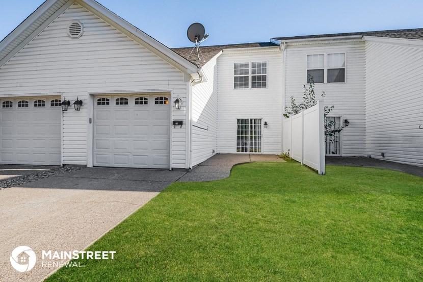 a white house with two garages and a lawn