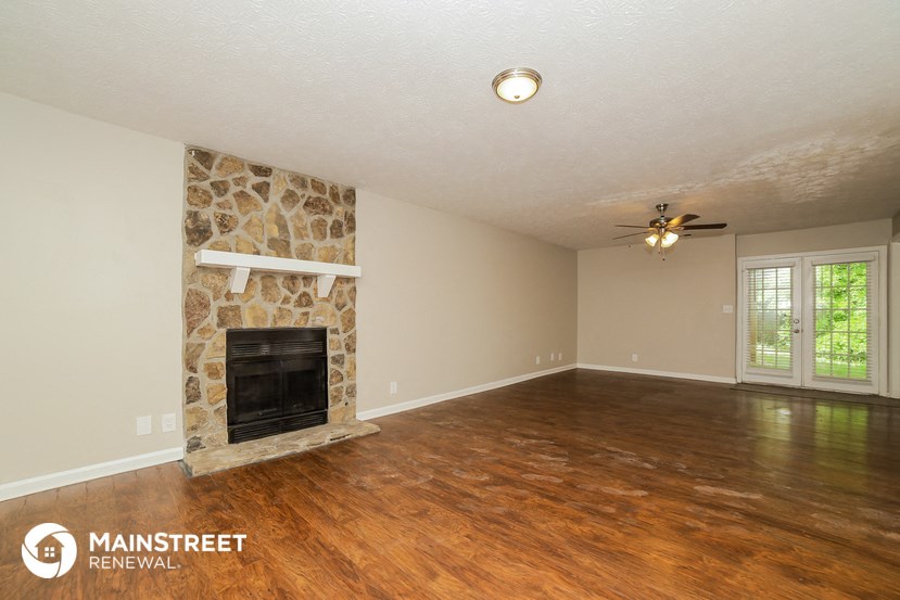 the living room of a house with a stone fireplace and wooden floors