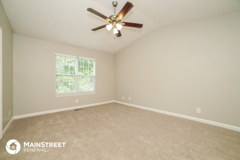 the master bedroom has a carpeted floor and a ceiling fan