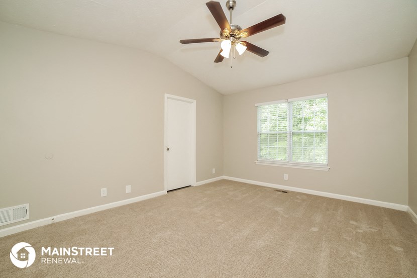 the master bedroom has a carpeted floor and a ceiling fan