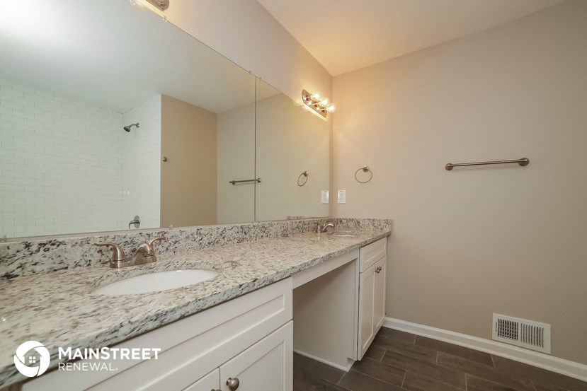 the master bathroom has a large vanity and a large mirror
