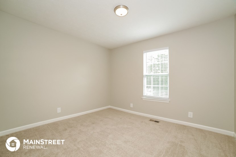 the spacious living room with carpeting and a window