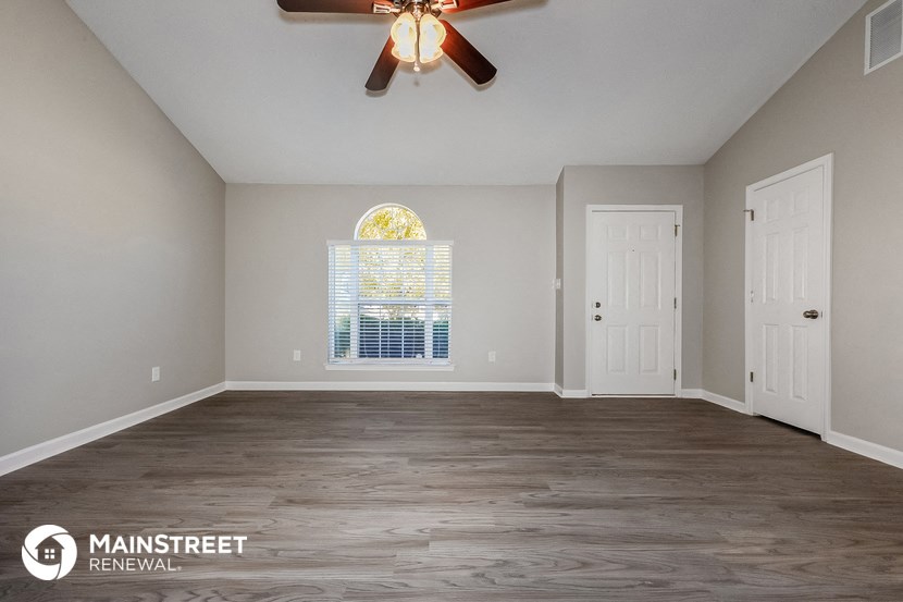 an empty living room with a ceiling fan and a window