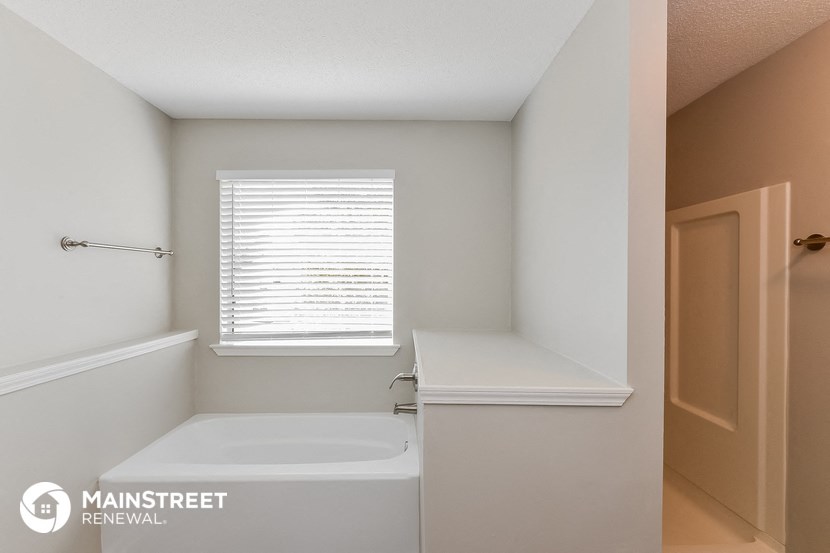 a bathroom with a tub and a sink and a window