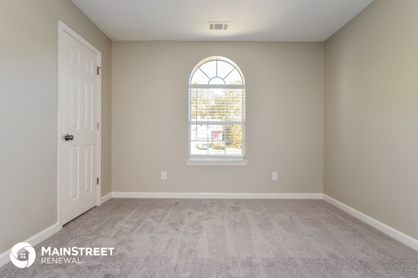 an empty room with a white door and a window