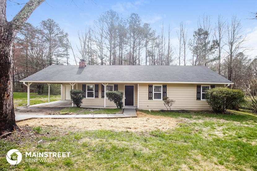 a small yellow house with a yard and a tree