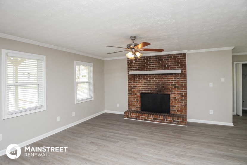 a living room with a brick fireplace and a ceiling fan