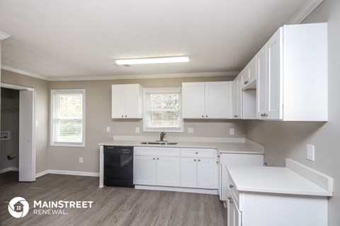a white kitchen with white cabinets and white counter tops and a black sink