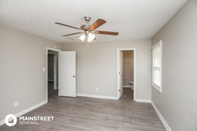 a living room with a ceiling fan and a door to a bathroom