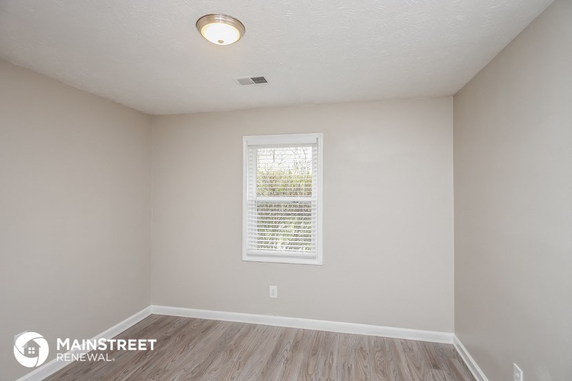 the spacious living room with wood flooring and a window