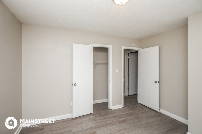 a bedroom with three closets and a wood floor and white walls