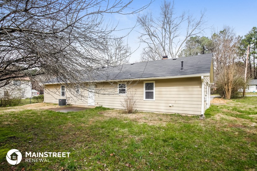the front of a small yellow house with a yard and grass